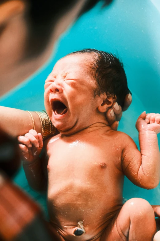 an infant crying with one foot on top of it