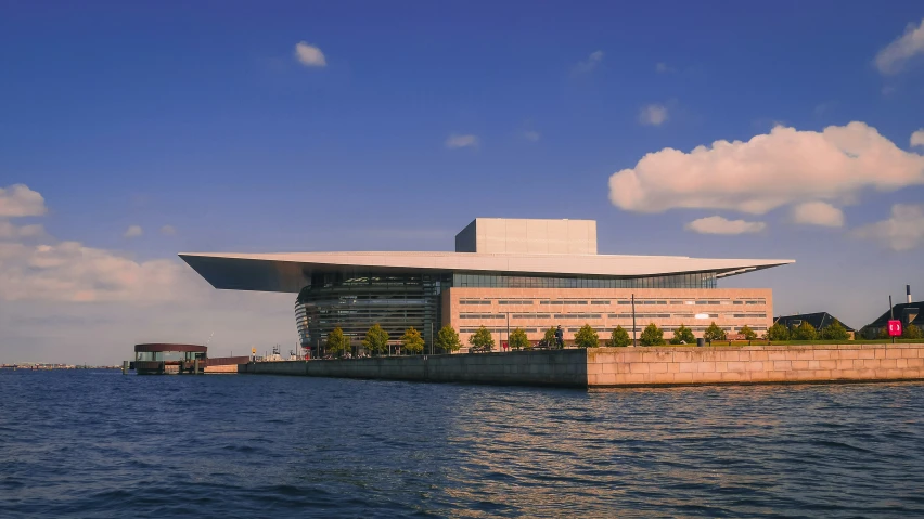 a building near a body of water with clouds above it