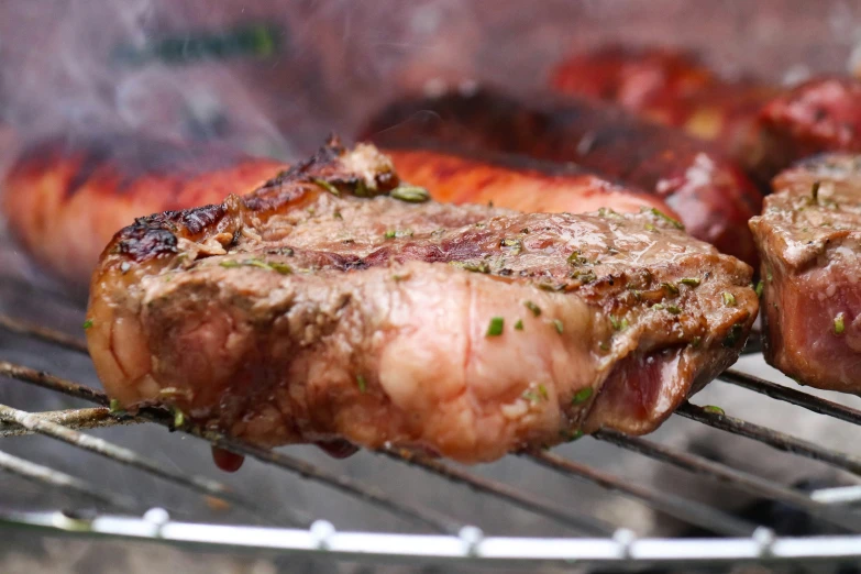 two steaks cooking on a bbq on a grill