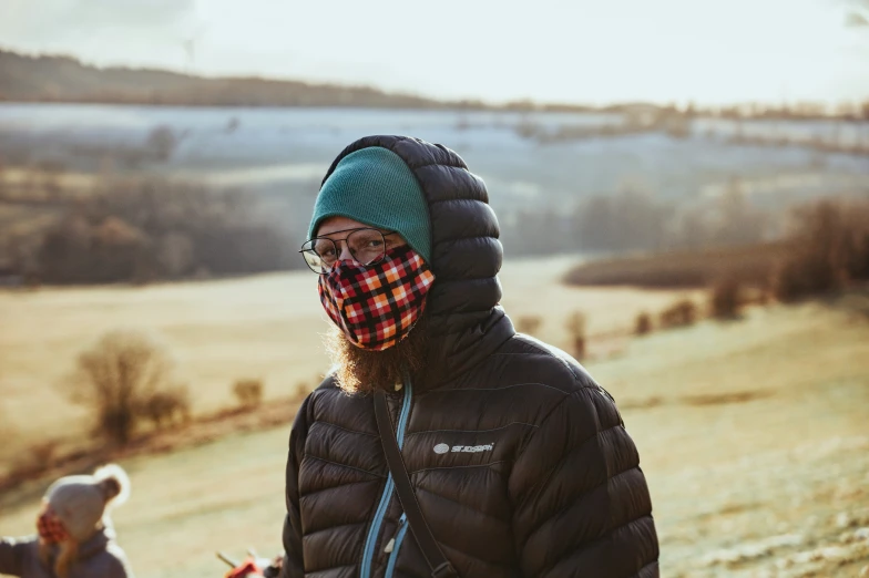 a man wearing a plaid bandana while standing in a field