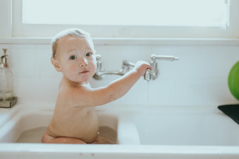 a toddler is sitting in the bathroom sink