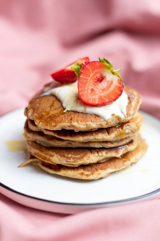 four pancakes with strawberries and whipped cream on top