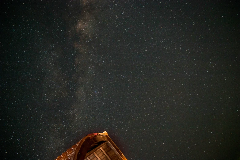 night sky with star trails and a tent in foreground