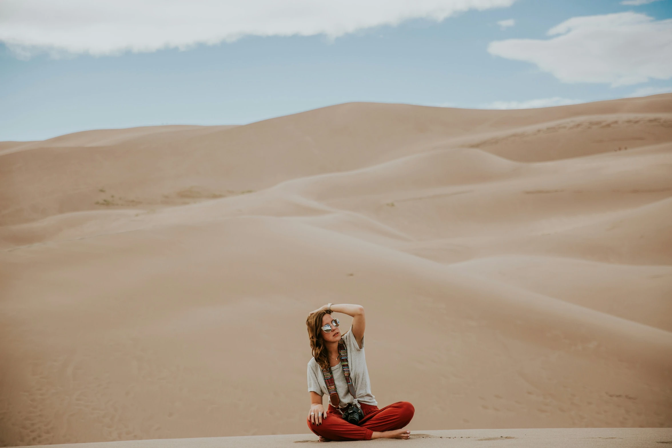 a woman sitting on the ground wearing a hat