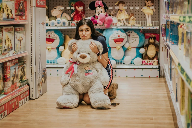 a woman is sitting on the floor and hugging a teddy bear