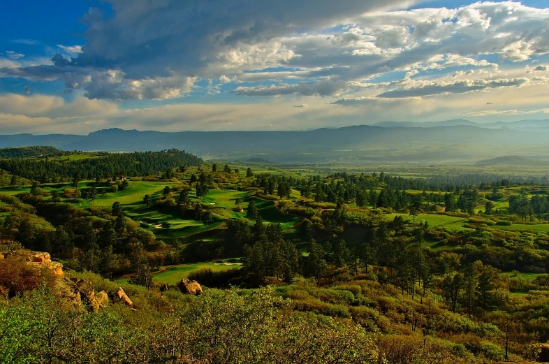 an open grassy valley surrounded by mountains on a cloudy day