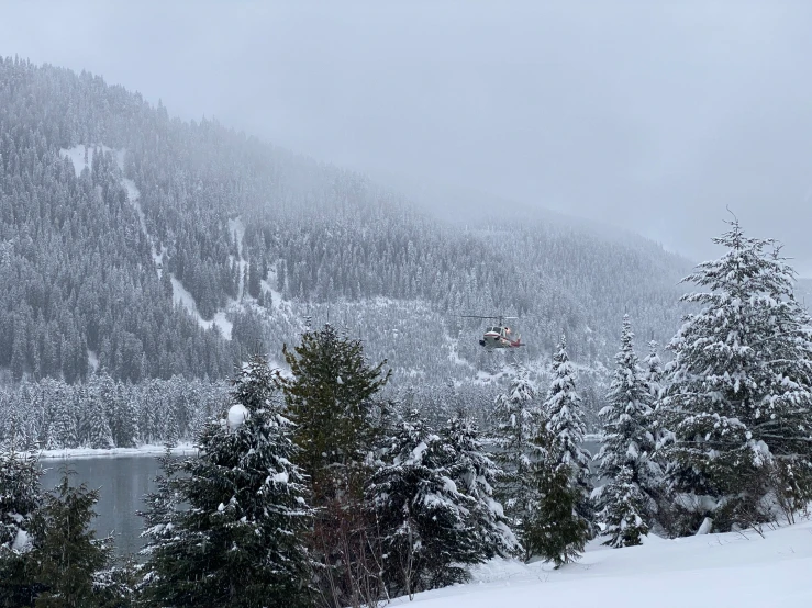 a lake with snow on the mountains and trees surrounding it