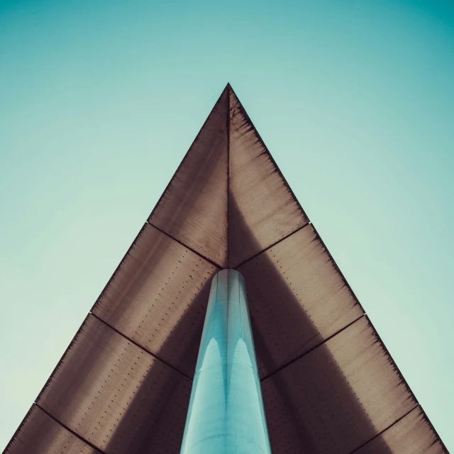 the top of a triangle shaped building with blue skies in background