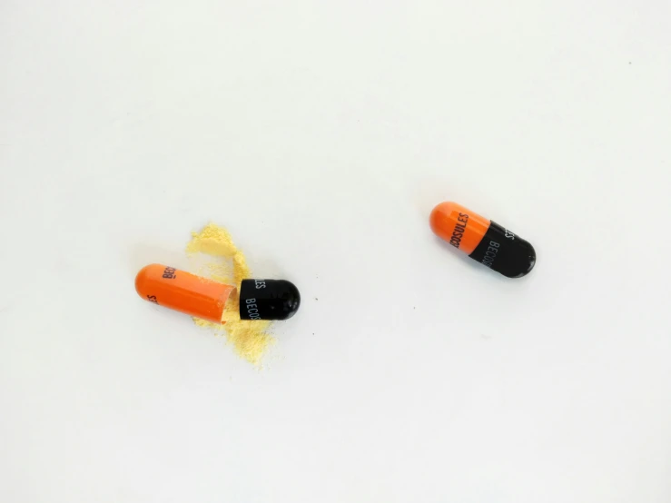 three different orange and black pill bottles on white surface