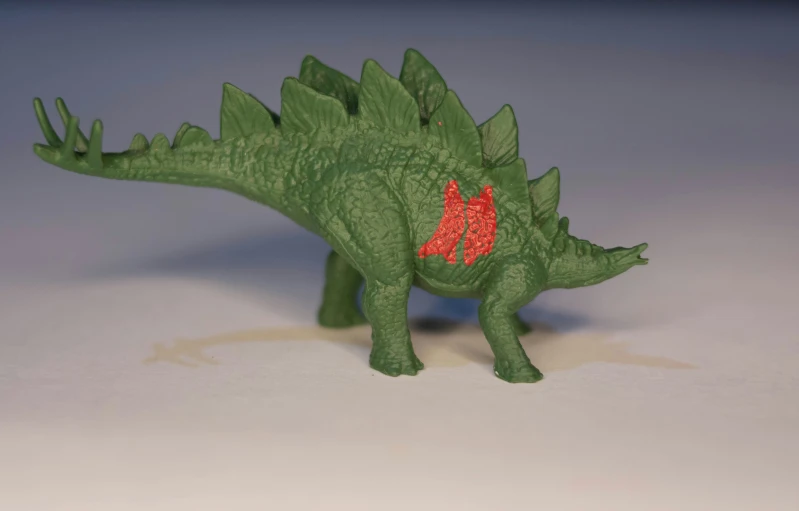 a toy dinosaur standing with red spots on its eye