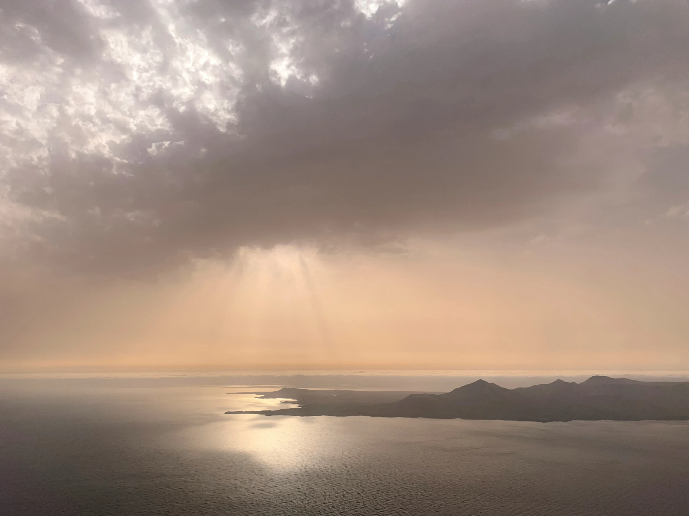 the view of the sea and sun with a cloud above