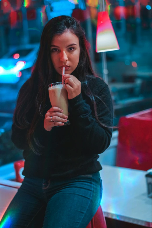 a woman sitting at a restaurant with an alcoholic beverage in her hand