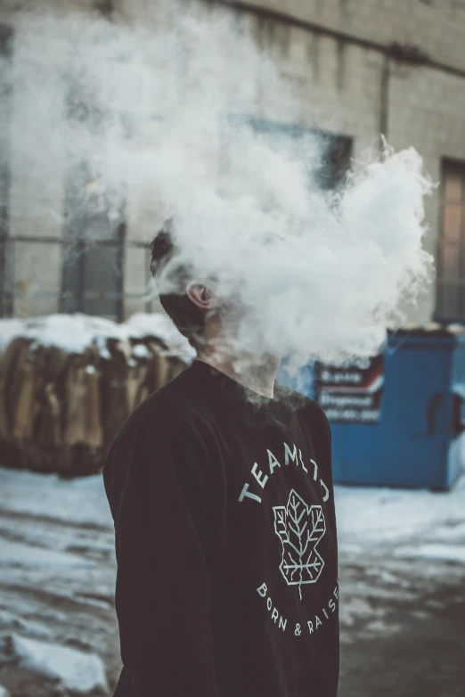 a person wearing a sweatshirt while smoking a marijuana plant