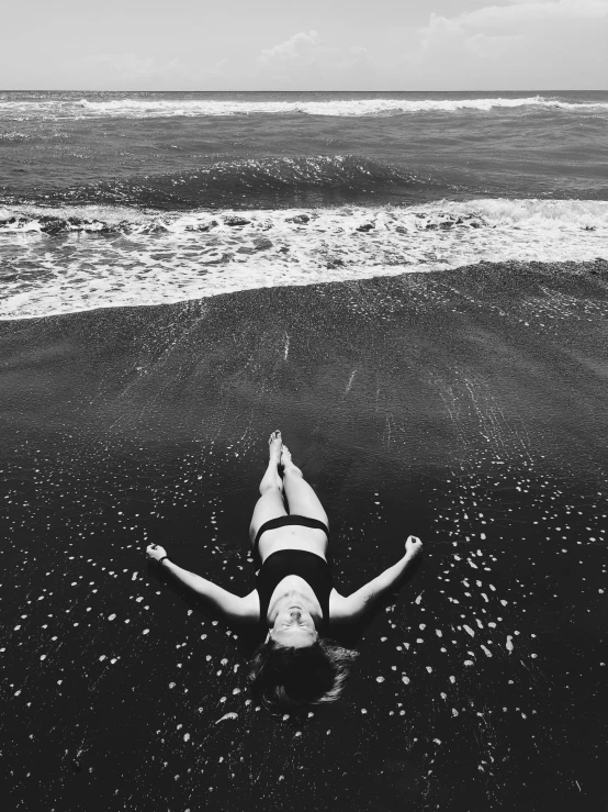 a person lays on top of the black sand