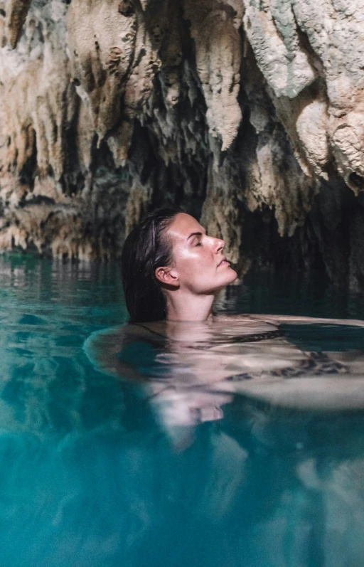 a woman in a body of water staring at rocks