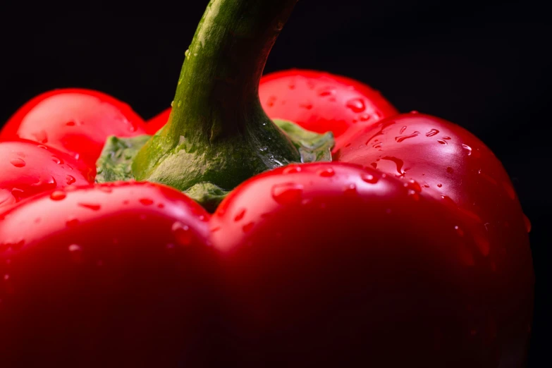 a green stem is hanging from a red pepper