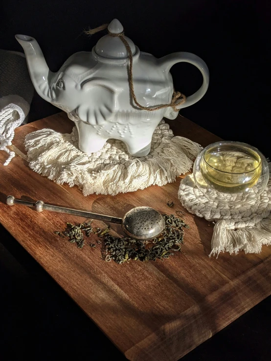 a white teapot on a wooden board with other items