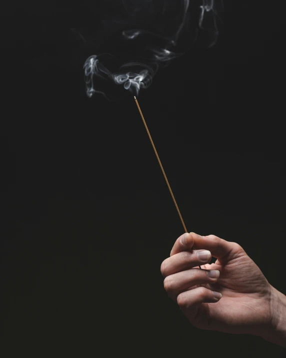 a person is holding a smoke wand in their hand
