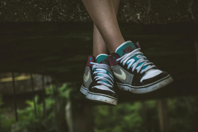 a pair of sneakers hanging from a metal fence