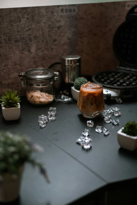 there is a drink, plants, and ice cubes on the table