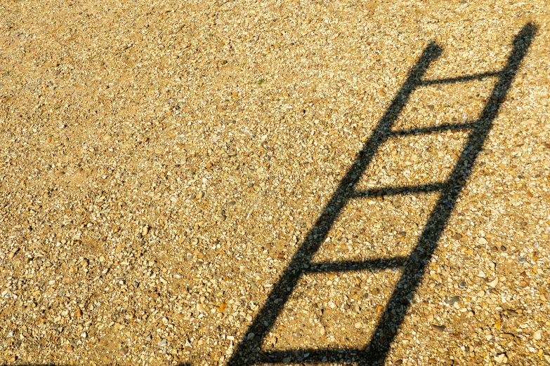 a small ladder casts a shadow on the ground