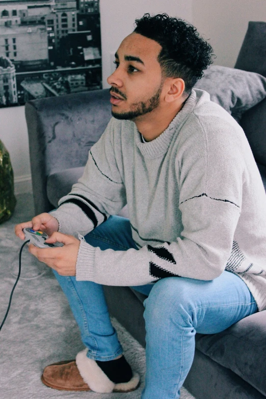 young man with dark hair wearing grey sweater playing a video game