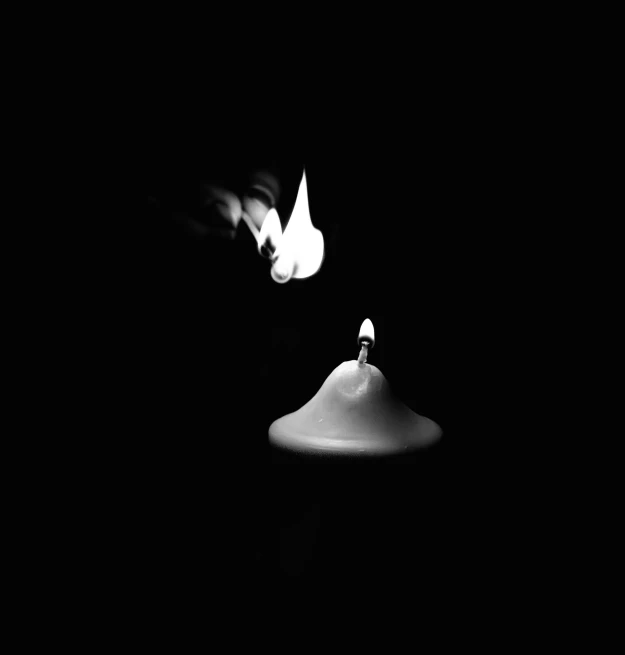 two lit candles are sitting in the dark