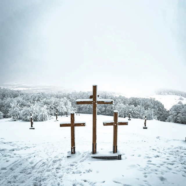 two crosses are on the top of a snowy hill