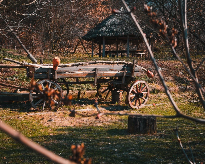 an old wooden wagon sitting outside in front of trees