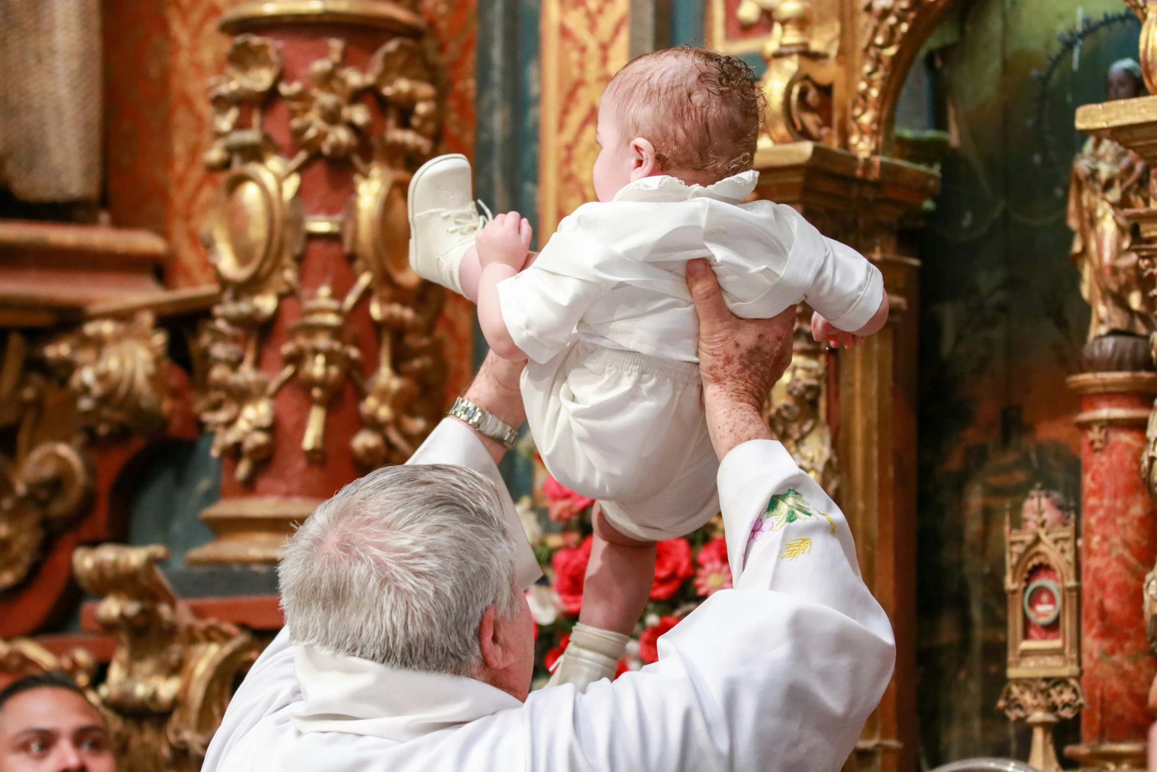 a priest in white robes holding a small child
