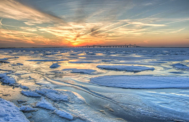 a sunset with a small section of the water partially covered in ice