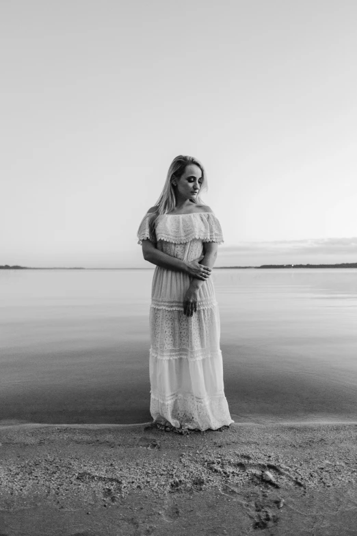 a woman standing next to the ocean in a white dress