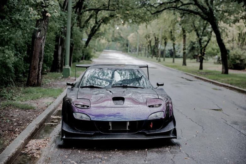 a car parked on the side of the road in front of trees