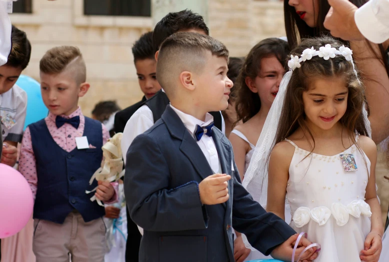 a boy and girl standing beside each other in front of balloons