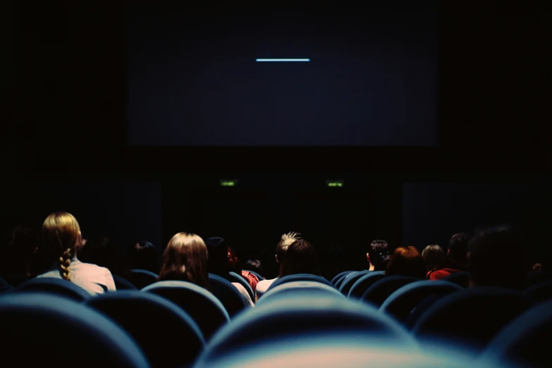 people sit in the middle of an auditorium watching television
