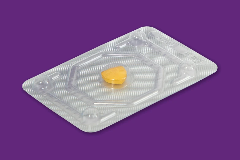 a package with a yellow pill laying on it