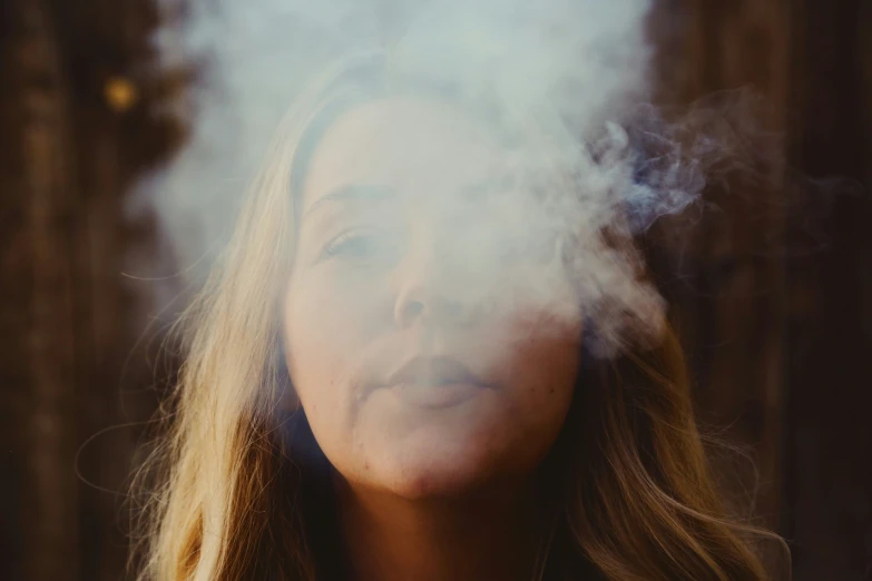 a woman's face being obscured by smoke and wood