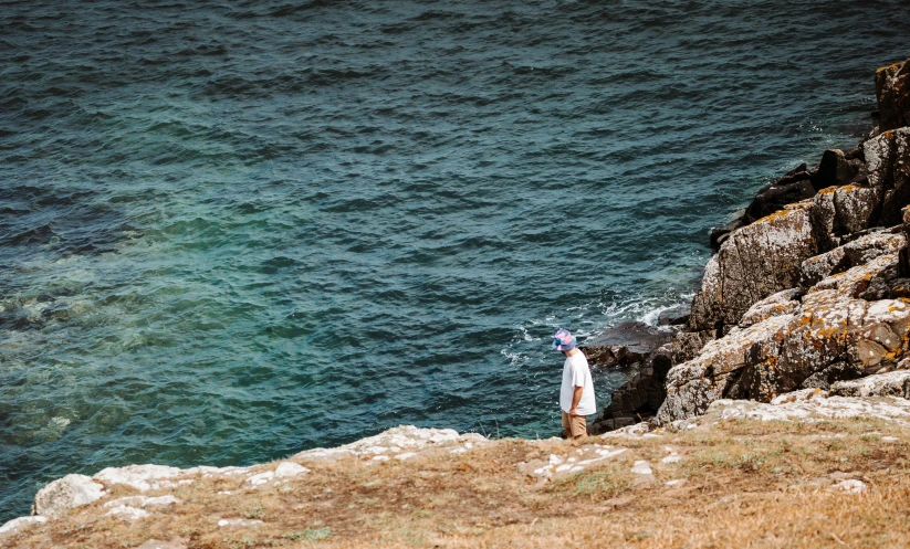 a person that is standing in the grass next to the water