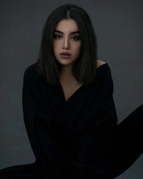 a young woman sitting in a dark pose