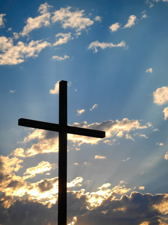 a cross is silhouetted against a dramatic sky