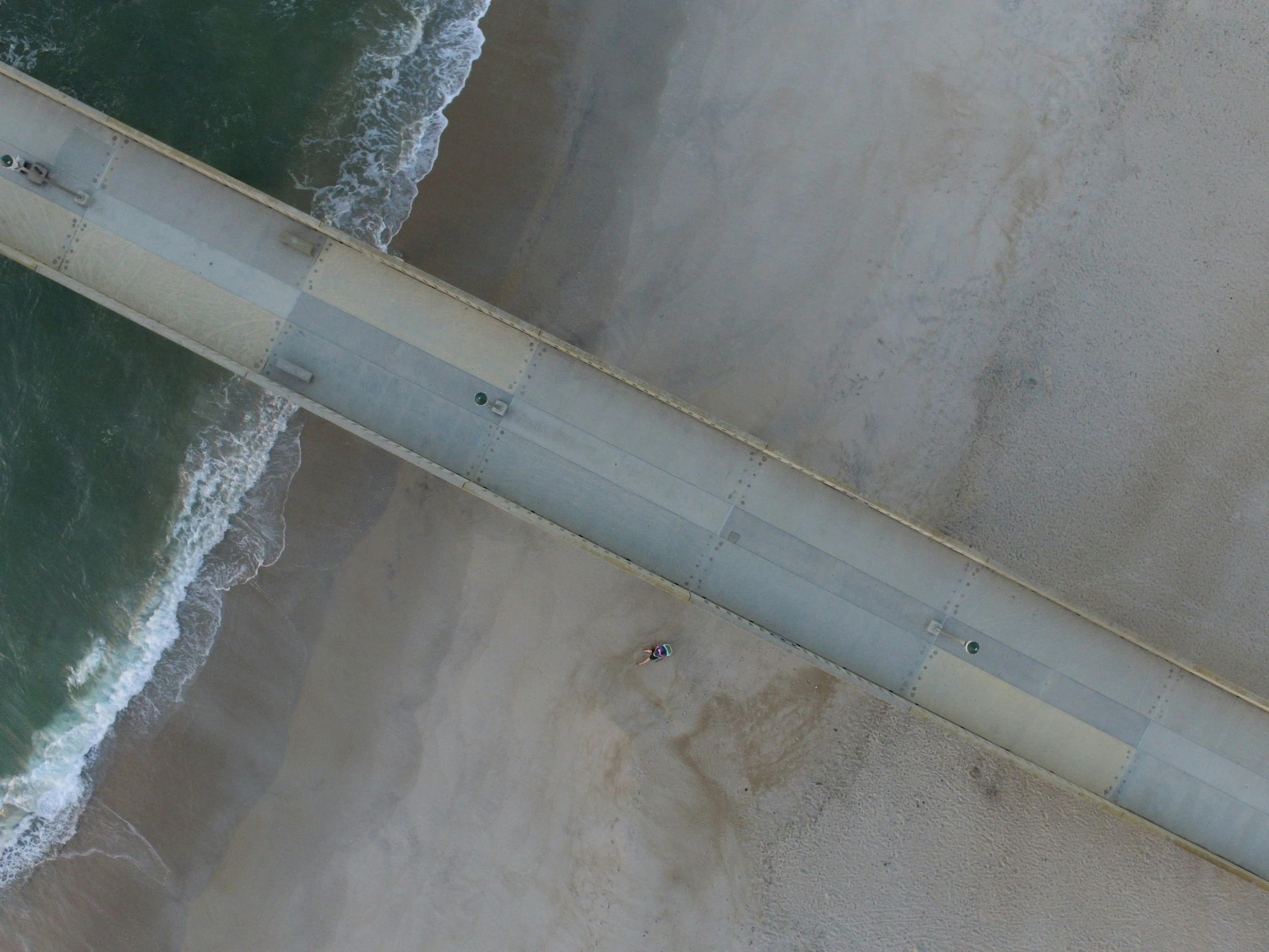 the aerial view of a beach with people walking over it