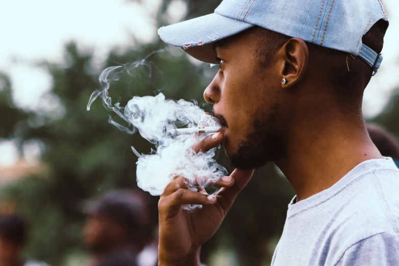 a young man is smoking an electronic cigarette