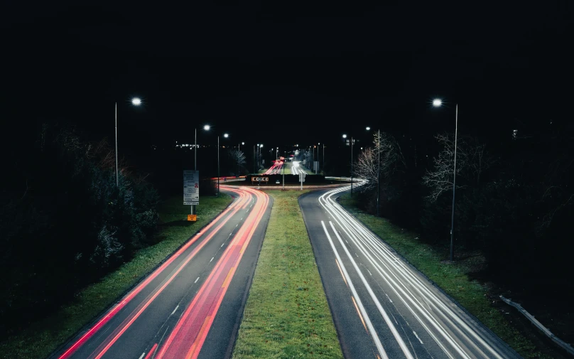 a night time highway with the lights turned on and the cars parked in front