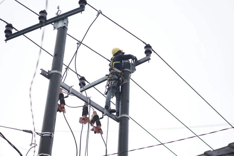 electric engineer at an overhead power line on a grey day