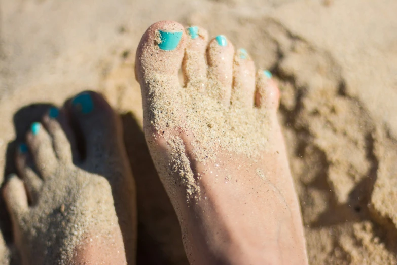 a person with blue toes standing in the sand