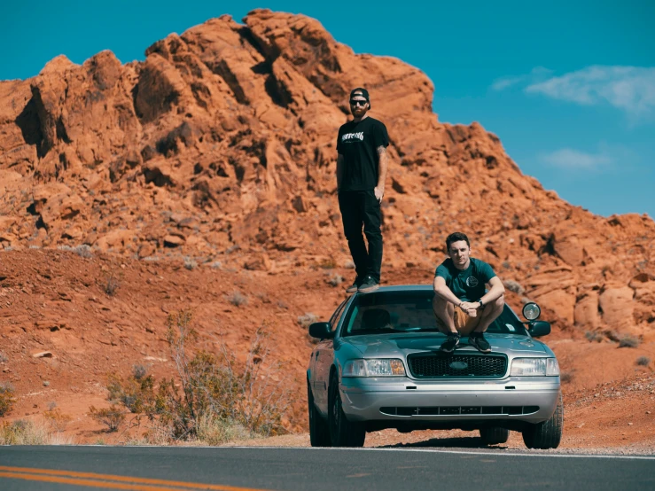 a person standing on the hood of a car and another man standing on top