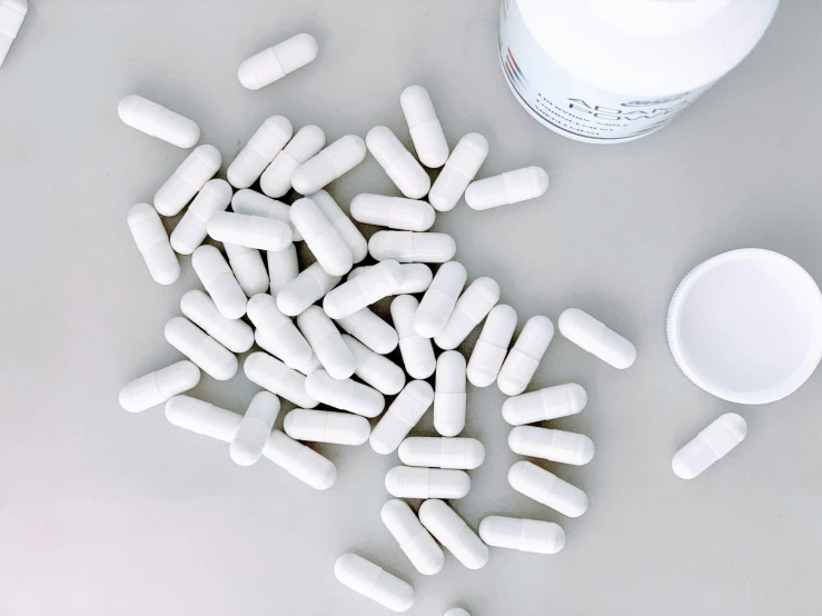 a large amount of pills sitting in front of a container