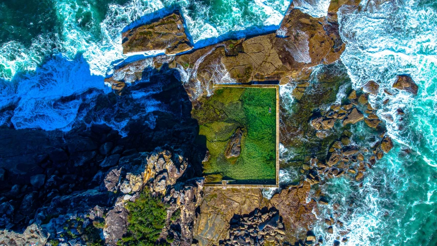 an aerial view shows the ocean with green grass in the middle