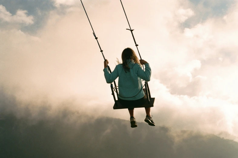 a girl sitting on a swing with two handles above her head