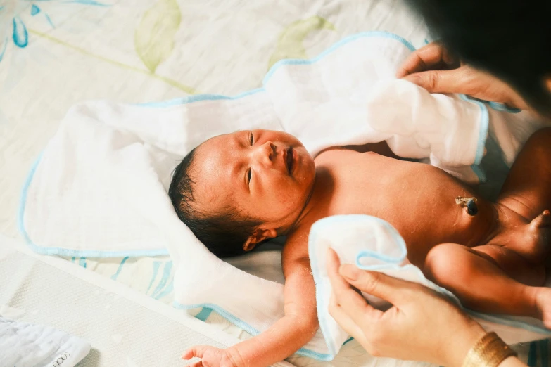 an adult feeding a baby in a bed with pillows